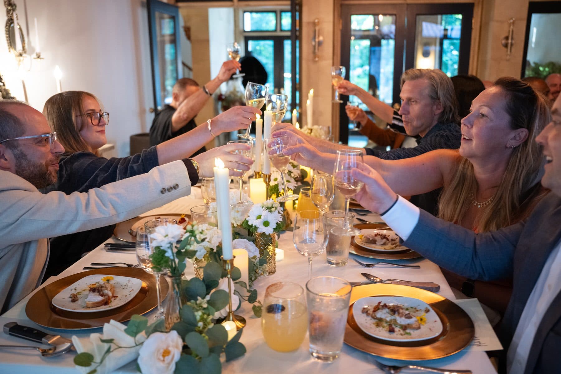 Guests raising a toast across a candlelit dinner table